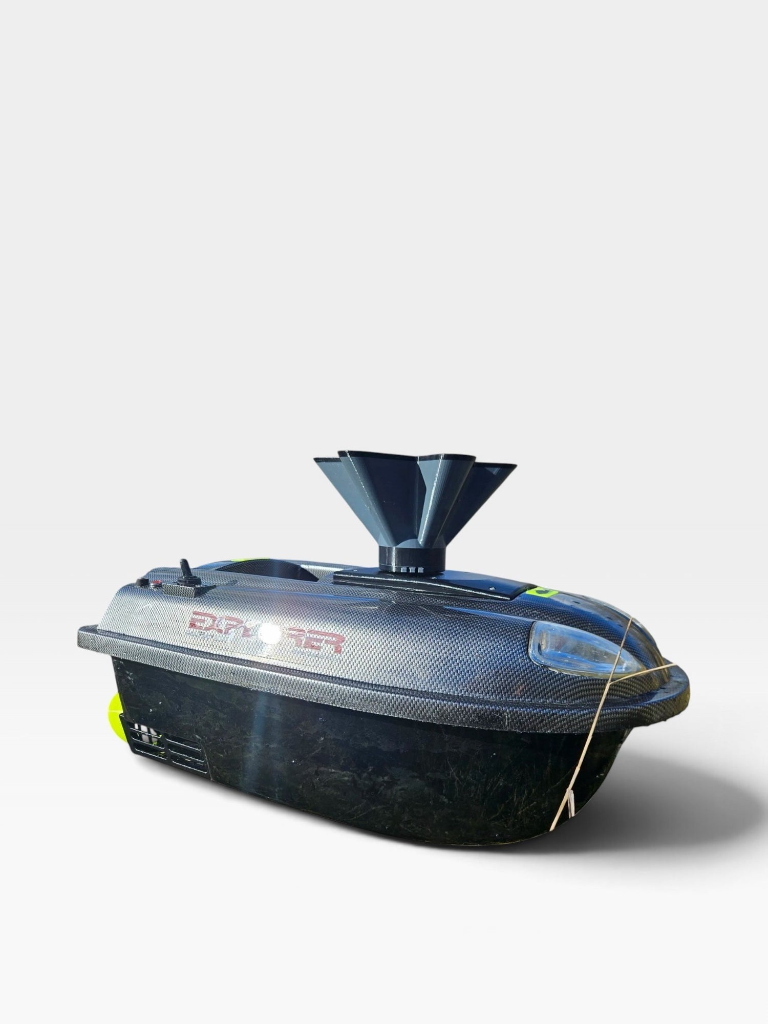 Disperseur d'appât PrintForFishing installé sur un bateau amorceur Quad Bait Boat v2 noir effet carbone au bord de l'eau